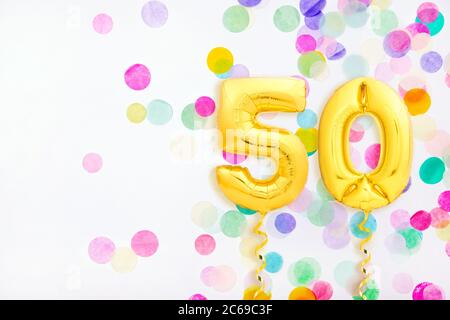 Numéro 50 cinquante en ballons gonflables dorés avec rubans dorés sur fond de confetti coloré Banque D'Images