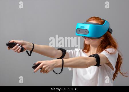 La technologie 3D, la réalité virtuelle, de divertissement, d'éducation concept. Les jeunes red-haired woman wearing white t-shirt à l'aide de casque vr avec tête à disp Banque D'Images