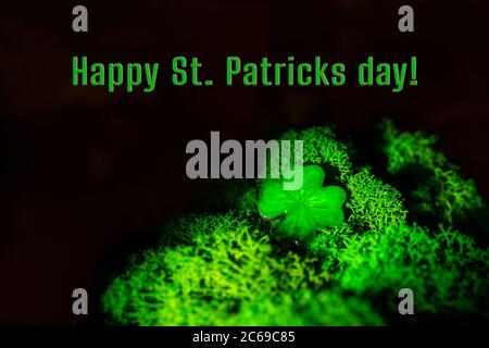 Arrière-plan de la Saint-Patrick. Trèfle chanceux dans la mousse naturelle dans l'obscurité. Vue de dessus, espace de copie. Bonne inscription à la Saint Patrick. Banque D'Images