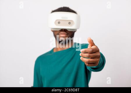 Guy africains en vert poolover de réalité virtuelle en 3d à l'aide de casque pour téléphone intelligent, en tendant la main avec open palm comme si nous invitant à j Banque D'Images