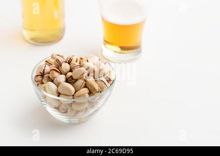 Traditions de bière et hors-d'œuvre. Pistaches avec pelure dans une plaque de verre, à proximité sont verre inachevé de la bière et de la bouteille Banque D'Images