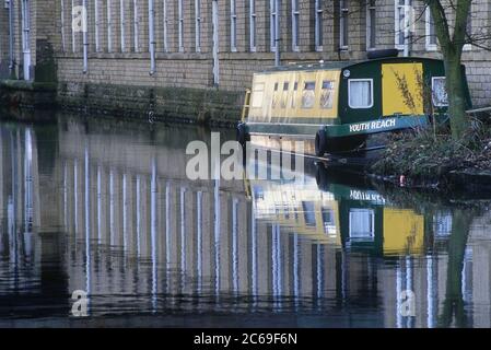 Un moulin à barques et sels amarrés se reflète dans le canal de Leeds et Liverpool à Saltaire, West Yorkshire, Angleterre, Royaume-Uni Banque D'Images