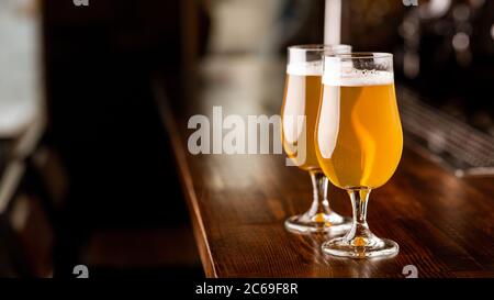 Service au pub. Verres avec bière dans la lumière sur le comptoir en bois Banque D'Images