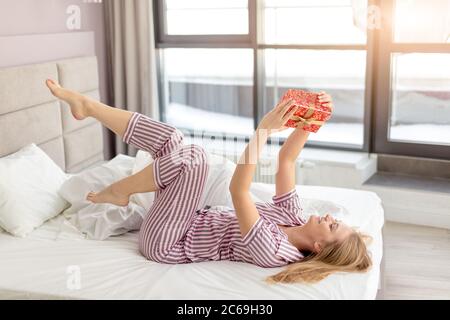 une jeune fille gaie est heureuse d'obtenir un cadeau pour son anniversaire. photo de vue latérale pleine longueur, surprise de mari Banque D'Images