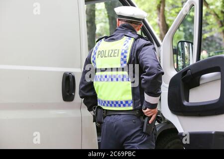 24 avril 2020, Hambourg: Un policier est en service dans un poste de contrôle de la police à Max-Brauer-Allee. Il tient une main sur son arme de service. La police de Hambourg a vérifié le respect par les conducteurs du district d'Altona de l'interdiction de la conduite de diesel. Il y a une interdiction de conduire pour les voitures et les camions diesel plus anciens à près de 600 mètres de Max-Brauer-Allee. Les infractions seront passibles d'amendes. Photo : marques de bodo/dpa Banque D'Images