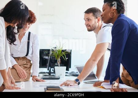 divers employés de l'entreprise discutent en groupe, discutent au bureau blanc. Exposition d'homme caucasien sur papier Banque D'Images