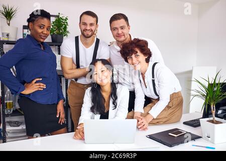 Travail conjoint de groupes multiethniques de personnes créatives réunis près d'une femme asiatique assis avec un ordinateur portable, regardez la caméra. Des affaires pour les gens concep Banque D'Images