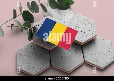 Drapeau tchadien sur pierres élégantes hexagonales. Arrière-plan rose de l'espace de copie. Flat Lay, vue de dessus concept national minimal. Banque D'Images