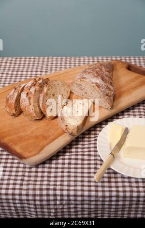 Pain de pâte aigre avec raisins secs et zeste mélangé du marché agricole à Stroud coupé en tranches sur une planche à pain faite à la main et servi avec du beurre. Banque D'Images