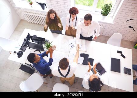 Bon travail d'une équipe d'affaires réussie après la réunion, asseyez-vous autour de la table pendant que les chefs se secouent la main. Rencontre internationale, partenariat multiethnique Banque D'Images