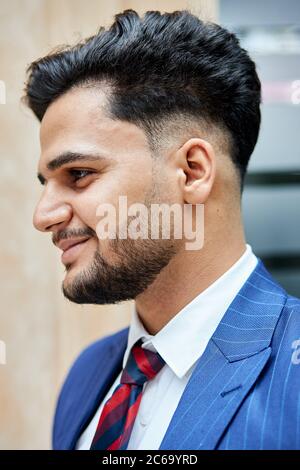 Souriant arabe gars. Soies sur le visage de brunette, cheveux modernes. Arrière-plan de la rue Banque D'Images