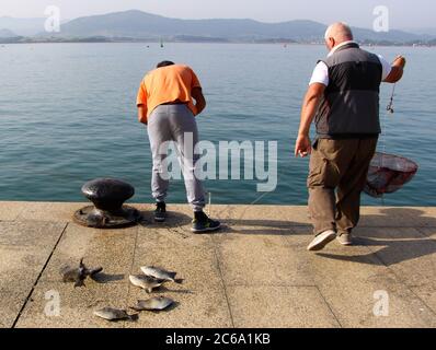 Deux pêcheurs avec pêcheur gris pêché Balistes capriscus tôt le matin pêche à la canne et à la ligne dans la baie de Santander Cantabria Espagne Banque D'Images