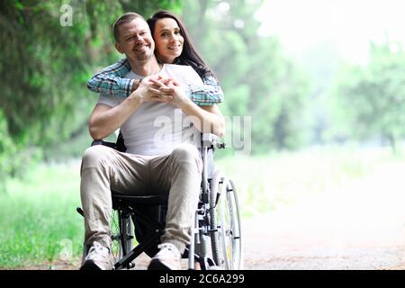 Une femme encadre un homme en fauteuil roulant Banque D'Images