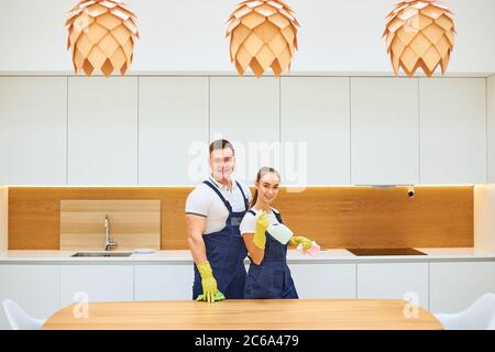 Travail d'équipe réussi de deux concierges après le travail, posant dans les uniformes bleus de travail, regardez la caméra. Cuisine blanche Banque D'Images