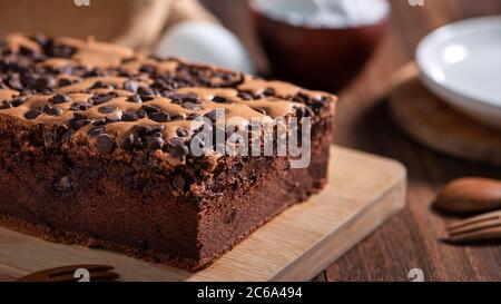 Gâteau éponge traditionnel taïwanais au goût de chocolat (taïwanais castella kasutera) sur une table de fond en plateau de bois avec les ingrédients, gros plan. Banque D'Images