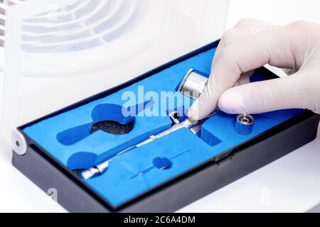 Main humaine dans un gant de protection retirer l'outil de brosse à air pour peindre les ongles de la boîte en salon Banque D'Images