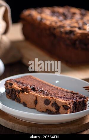 Gâteau éponge traditionnel taïwanais au goût de chocolat (taïwanais castella kasutera) sur une table de fond en plateau de bois avec les ingrédients, gros plan. Banque D'Images