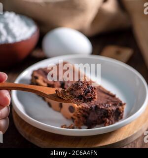 Gâteau éponge traditionnel taïwanais au goût de chocolat (taïwanais castella kasutera) sur une table de fond en plateau de bois avec les ingrédients, gros plan. Banque D'Images