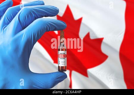 Drapeau canadien avec le concept Covid-19 du coronavirus. Médecin avec des gants médicaux de protection bleus tenant une bouteille de vaccin. Virus épidémique, COV-19, Corona vir Banque D'Images