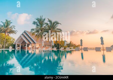 Magnifique piscine et coucher de soleil. Luxueux paysage tropical de plage, chaises longues et chaises longues et reflet de l'eau. Des vacances incroyables, des vacances d'été Banque D'Images