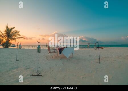 Dîner romantique sur la plage avec coucher de soleil, bougies sur sable blanc doux. Vacances tropicales, vacances d'été. Voyage romantique en couple, dîner de luxe Banque D'Images