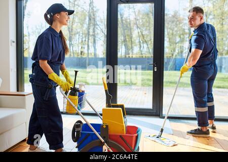 Les collègues hommes et femmes de la compagnie de nettoyage aiment travailler dans le service de nettoyage, le processus de nettoyage de la maison. Banque D'Images