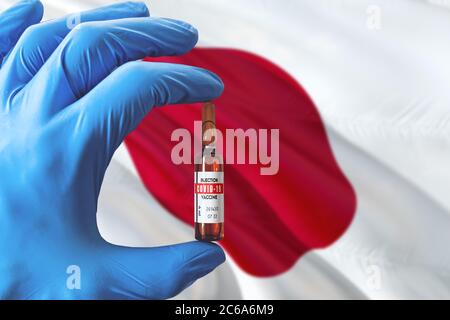 Drapeau japonais avec le concept Covid-19 du coronavirus. Médecin avec des gants médicaux de protection bleus tenant une bouteille de vaccin. Virus épidémique, COV-19, Corona viru Banque D'Images