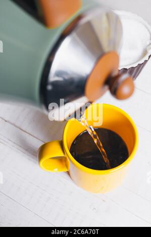 Préparation de café dans une tasse jaune tôt le matin Banque D'Images