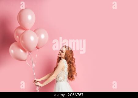 Portrait de caucasien apparence stand portant la robe de mariage avec ballons d'air roses. Heureux Banque D'Images