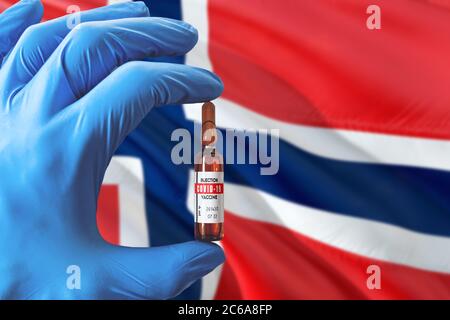 Drapeau norvégien avec le concept Covid-19 du coronavirus. Médecin avec des gants médicaux de protection bleus tenant une bouteille de vaccin. Virus épidémique, COV-19, Corona vir Banque D'Images