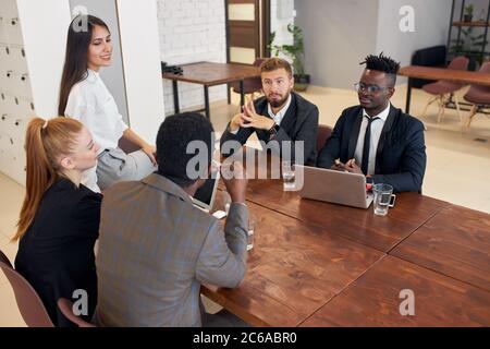 Les partenaires d'affaires écoutent l'homme africain assis sur une table ronde Banque D'Images