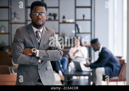 Homme d'affaires confiant portant un support en tuxedo classique posé dans un environnement de bureau et regarde la caméra. Concept de personnel d'affaires Banque D'Images