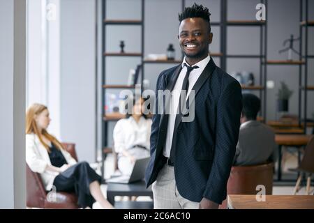 Homme d'affaires personnel portant un classique noir Tuxedo stand posant dans l'environnement de bureau et regarder la caméra et sourire . Concept de personnel d'affaires Banque D'Images
