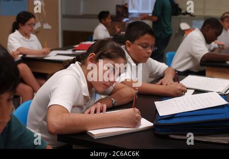 Austin, Texas États-Unis, novembre 2003 : les élèves de sixième année portant des uniformes scolaires écrivent des essais dans leurs cahiers tout en étant assis à leur bureau pendant le cours à St. Ignatius Catholic School, une école catholique paroissiale privée. ©Bob Daemmrich Banque D'Images