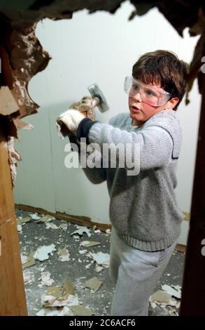 Austin Texas États-Unis, 2003 : un garçon de huit ans portant des lunettes de sécurité utilise un marteau de traîneau pour aider à briser les cloisons sèches sur le projet de rénovation de bureau. Modèle validé. ©Bob Daemmrich Banque D'Images