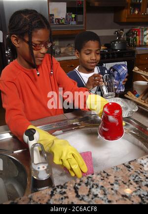 Austin, Texas USA, décembre 2003 : fille afro-américaine (10) et frère (8) lavent la vaisselle à la maison. Modèle validé. ©Bob Daemmrich Banque D'Images