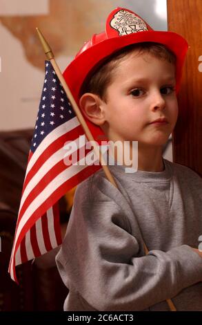 Austin, Texas États-Unis, 31 janvier 2002 : Robin David Daemmrich, 5 ans, pose avec un casque de pompier et un drapeau américain pendant le jeu. Il dit qu'il veut être un brave pompier quand il sera grand. ©Bob Daemmrich Banque D'Images