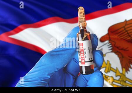 Drapeau des Samoa américaines avec le concept Covid-19 du coronavirus. Un médecin portant des gants médicaux de protection bleus tient un flacon de vaccin. Coronavirus covid 19 Banque D'Images