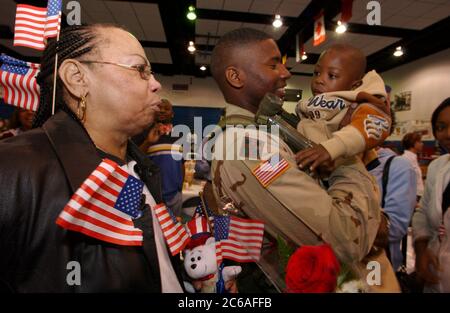 Fort Hood, Texas États-Unis, 16 février 2004 : environ 60 soldats des États-Unis La 4e division d'infanterie de l'armée basée à fort Hood est revenue lundi après-midi après un déploiement de près d'un an en Irak et a été accueillie par des membres de la famille à la base tentaculaire au nord d'Austin. Mary Savannah, à gauche, regarde son fils, le sergent Kendrick Savannah, hisser son fils, Tre (3) à leur réunion. ©Bob Daemmrich/The image Works Banque D'Images