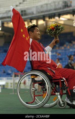 Athènes, Grèce 23SEP04: Les Jeux Paralympiques le haut cavalier chinois Bin Hou lève le drapeau chinois alors qu'il reconnaît les encouragements de la foule lors de sa cérémonie de médaille d'or à la compétition athlétique des Jeux Paralympiques au stade olympique. ©Bob Daemmrich Banque D'Images