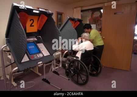 Austin, Texas États-Unis, 19 octobre 2004: Une électeur précoce en fauteuil roulant jette son bulletin de vote dans un établissement de vie senior à l'élection générale de 2 novembre. ©Bob Daemmrich Banque D'Images