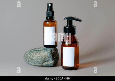 Ensemble de flacons en verre ambré foncé à usage cosmétique avec étiquettes vierges. Savon naturel biologique pour salle de bains et spray pour le corps sur pierre. Design de l'emballage des produits de beauté. Banque D'Images