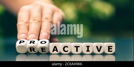 La main tourne les dés et change le mot réactif à proactif. Banque D'Images