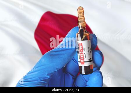 Drapeau japonais avec le concept Covid-19 du coronavirus. Médecin avec des gants médicaux de protection bleus tient un flacon de vaccin. Coronavirus covid 19 recherche sur le vaccin Banque D'Images
