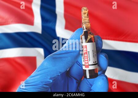 Drapeau norvégien avec le concept Covid-19 du coronavirus. Un médecin portant des gants de protection bleus tient une bouteille de vaccin. Coronavirus covid 19 vaccin SPC Banque D'Images