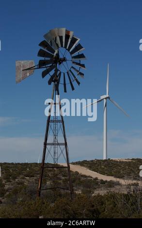 Iraan, Texas États-Unis, 18 février 2004 : un moulin à vent de ferme à l'ancienne se trouve devant des éoliennes modernes au parc éolien Desert Sky sur une mesa dans l'extrême ouest du Texas fournit l'électricité nécessaire au réseau électrique pour alimenter des milliers de foyers. ©Bob Daemmrich Banque D'Images