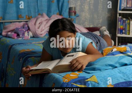 Monte Alto, Texas USA, décembre 11 2004 : une fille hispanique de neuf ans lit un dictionnaire dans sa chambre modèle publié ©Bob Daemmrich Banque D'Images