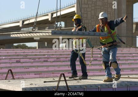 Comté de Williamson, Texas États-Unis, décembre 10 2004 : les travailleurs de la construction assistent alors que la section lourde de béton est abaissée par grue sur le pont supérieur pendant la construction de routes dans le centre du Texas sur la Texas State Highway 45. ©Bob Daemmrich Banque D'Images