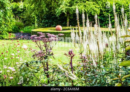 Un grand conteneur de plantes utilisé comme élément central dans un jardin d'été. Banque D'Images