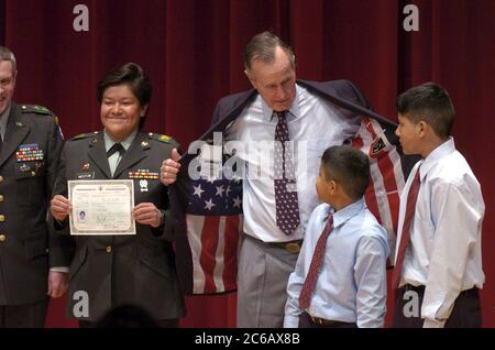 College Station, Texas, États-Unis, 11 mars 2005 : ancien États-Unis Le président George HW Bush montre son manteau de sport avec un drapeau américain doublé à Edward (9) et Alex (12) Weston alors que leur mère, la Sgt Rosa Weston, montre son nouveau certificat de citoyenneté américaine lors de cérémonies à l'Université A&M du Texas. ©Bob Daemmrich Banque D'Images